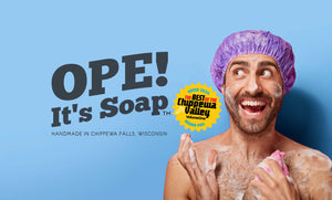 White man in purple shower cap, soap suds on body, excitedly looking at the Ope! It's Soap logo. A badge reading Voted 2024 The Best Of The Chippewa Valley Volume One Reader Poll is also displayed.