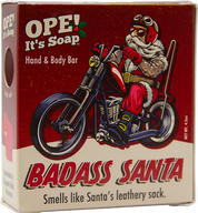 Ope! It’s Soap Badass Santa soap box featuring a tattooed Santa in biker gear riding a motorcycle, with bold red and cream packaging and the tagline “Smells like Santa’s leathery sack.”