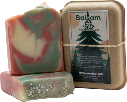 Image of three soaps stacked, one lying down, the other setting on top, next to a boxed soap.