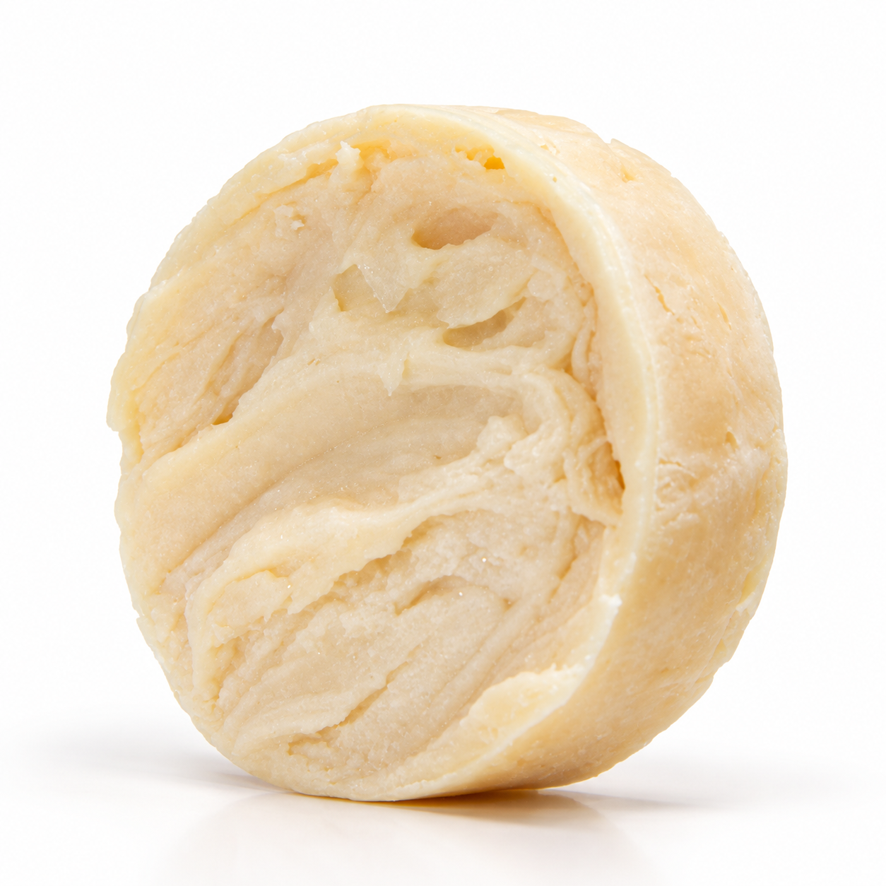 Cream colored handcrafted shave soap puck with a textured, swirled surface on a clean white background.