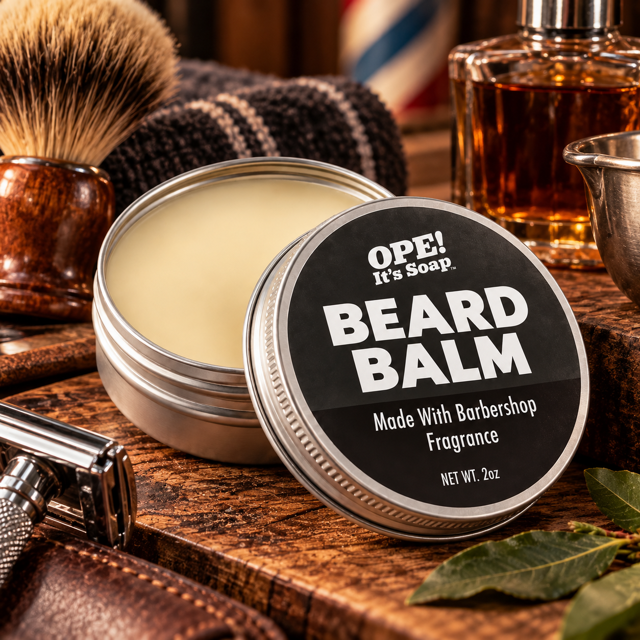 An open round tin of OPE! It's Soap Beard Balm sits on a wooden surface with its lid leaning against it. The lid is black with bold white text.