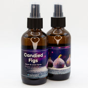 A pair of Candied Figs room & linen spray bottles, showing both sides of the label.