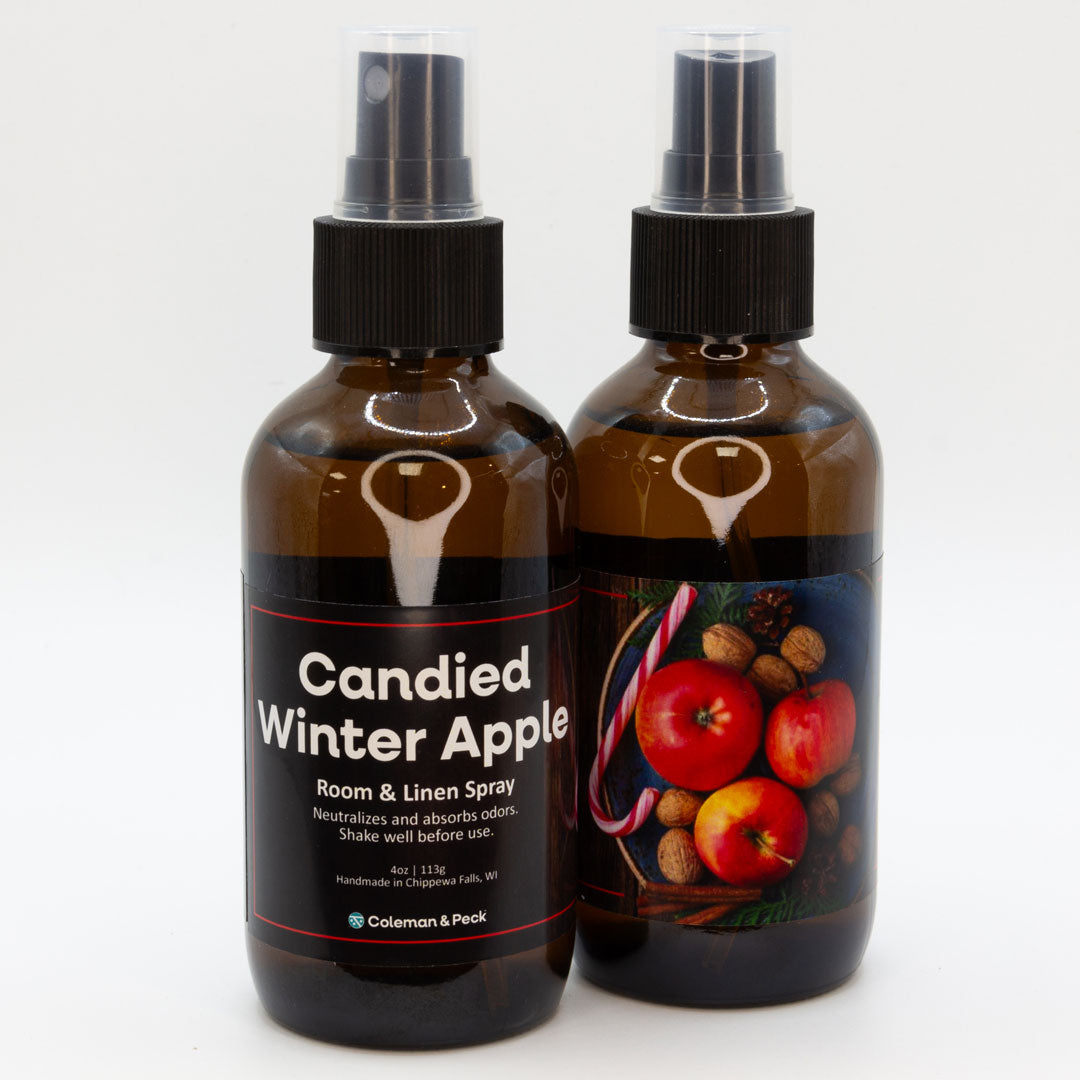 A pair of Candied Winter Apple room & linen spray bottles, showing both sides of the label.