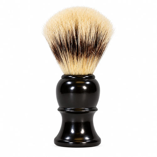 A shaving brush with a glossy black plastic handle and dense bristles that are cream and dark brown, photographed on a solid white background.