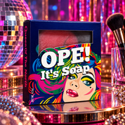 Ope! It’s Soap soap box displayed in a vibrant glam inspired scene with a disco ball, sparkling rhinestones, makeup brushes, and colorful pink, purple, and blue lighting.