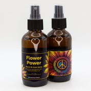 A pair of Flower Power room & linen spray bottles, showing both sides of the label.