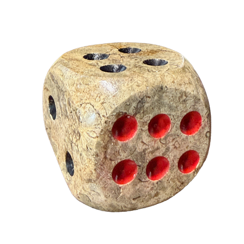 A textured, fossilized coral, stone-like die with a beige and brown marbled surface and bright red circular cutouts on the visible faces, isolated on a white background.