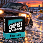 Ope! It’s Soap Geez Louise soap box displayed on an icy Wisconsin country road as a frightened woman loses control of her car on black ice at dusk.
