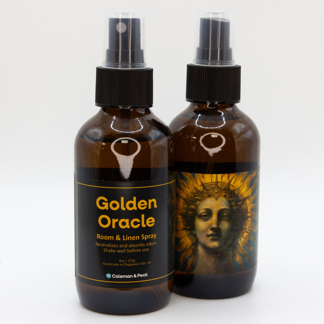 A pair of Golden Oracle room & linen spray bottles, showing both sides of the label.