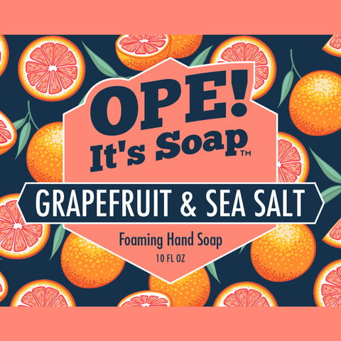 Grapefruit slices against navy and coral colored background, surrounding grapefruit and sea salt soap label