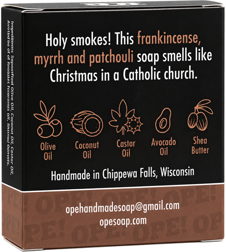 Back of the Ope! It’s Soap Holy Smokes soap box featuring the tagline “Holy smokes! This frankincense, myrrh and patchouli soap smells like Christmas in a Catholic church,” with illustrated icons highlighting the soap’s plant oils and shea butter.