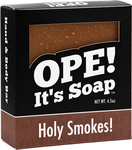 Ope! It’s Soap Holy Smokes soap box featuring black and warm brown packaging with a window showing the speckled brown soap bar inside.