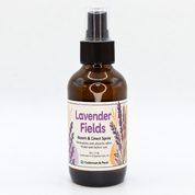Amber glass Lavender Fields room and linen spray bottle with a cream label featuring purple lavender botanicals and soft peach accents.