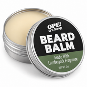 Open silver tin of Lumberjack Beard Balm with smooth cream colored balm and a tilted lid featuring a black and muted green Ope! It’s Soap label.