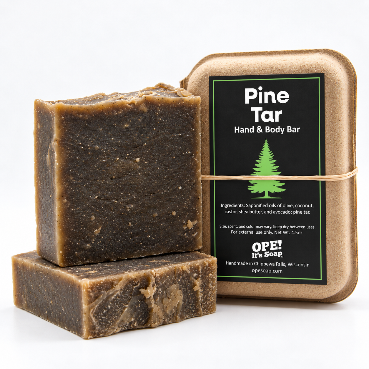 Two rustic, dark brown Pine Tar soap bars displayed beside eco friendly packaging with a black and green Ope! It’s Soap label on a clean white background.