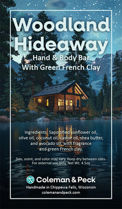 Woodland Hideaway soap ingredient card featuring an image of a cabin on a serene lake.