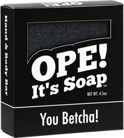 Ope! It’s Soap You Betcha! hand and body bar in black packaging with bold white lettering and a window revealing the dark, speckled soap inside.