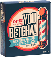 The front view of the Ope! It’s Soap You Betcha! soap box on a plain white background. The package is dark blue with large cream, red, orange, and teal graphics reading 'OPE! It's Soap YOU BETCHA! Barbershop Fragrance + Activated Charcoal' and shows a barber pole illustration.