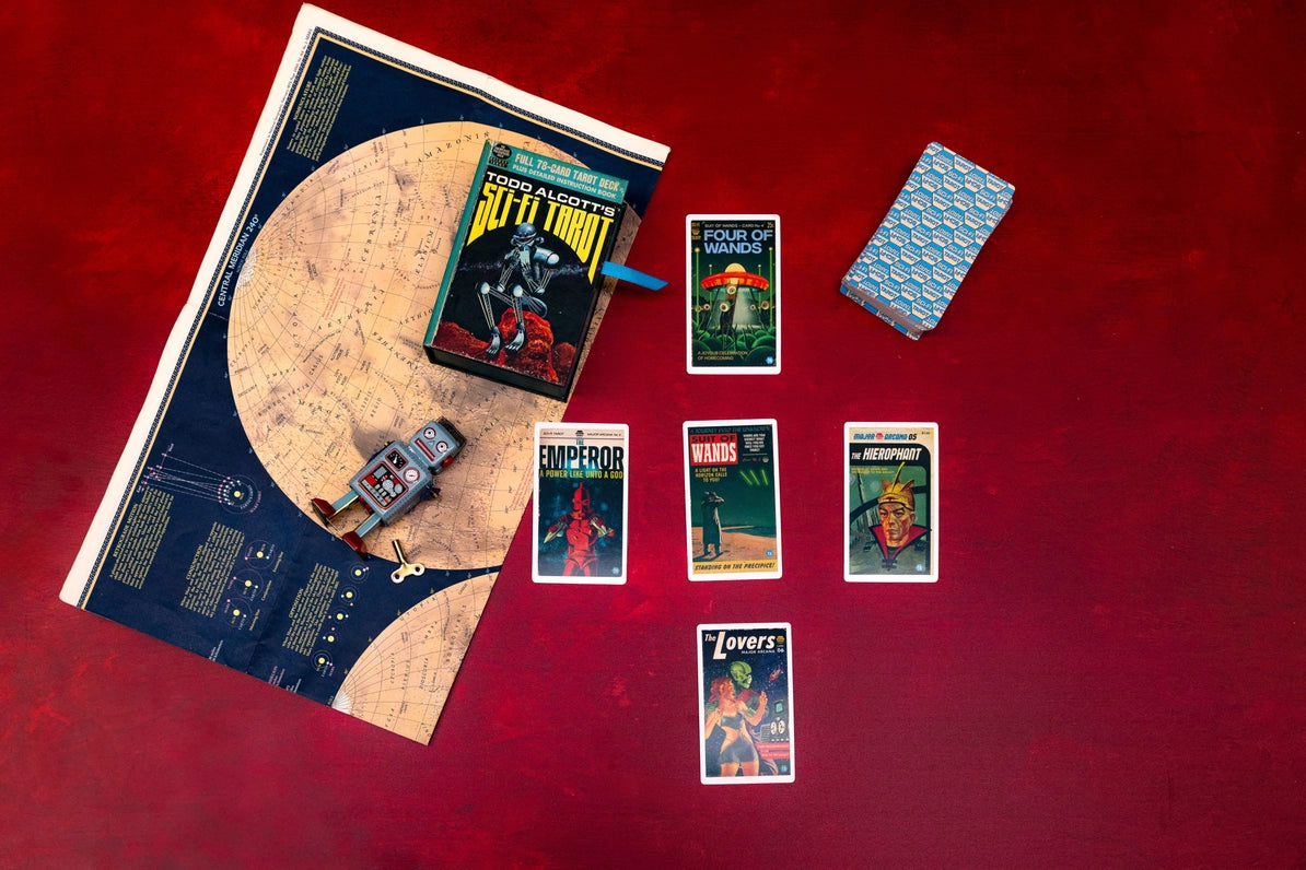 Collection of science fiction-themed books and cards on a red surface