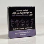 Back side of the For Crying Out Loud soap. Quote on box says, "For crying out loud, which one of youse swiped my black amber and lavender soap?" Box is black with light purple accents.