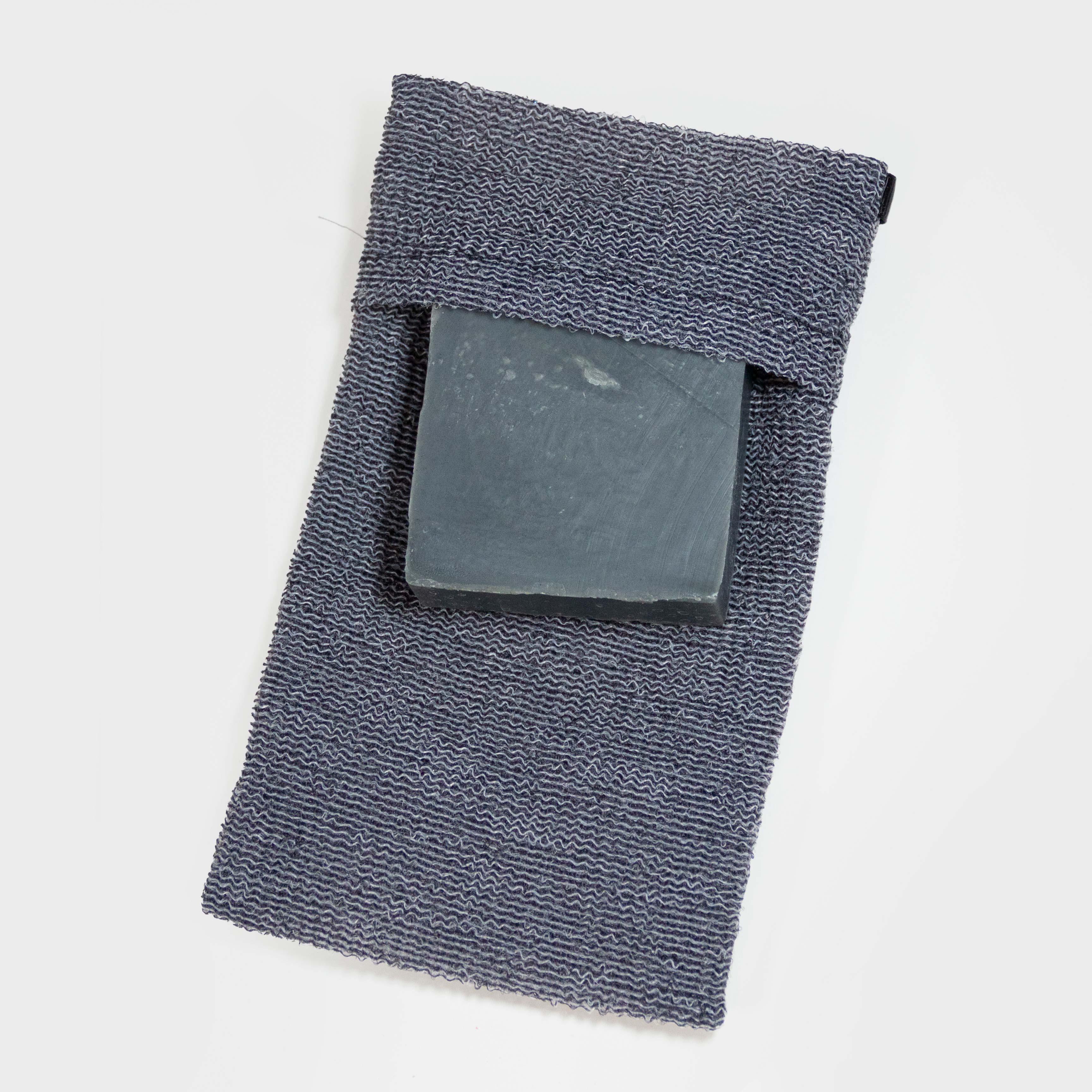 Photo of a single gray exfoliating soap bag, shown with a bar of soap being inserted.